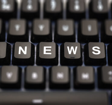 Online news, journalism concept. News word written on keypad. Black keys with white letters message for press articles on pc keyboard. Blur buttons background.