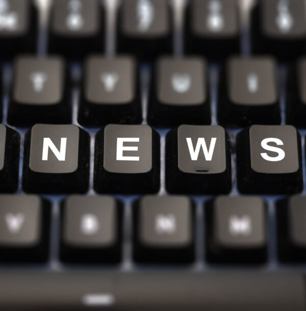 Online news, journalism concept. News word written on keypad. Black keys with white letters message for press articles on pc keyboard. Blur buttons background.